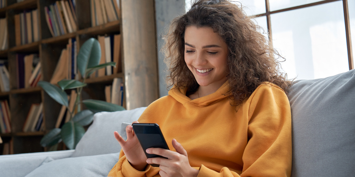 Woman in yellow sweater using a restaurant app on mobile device